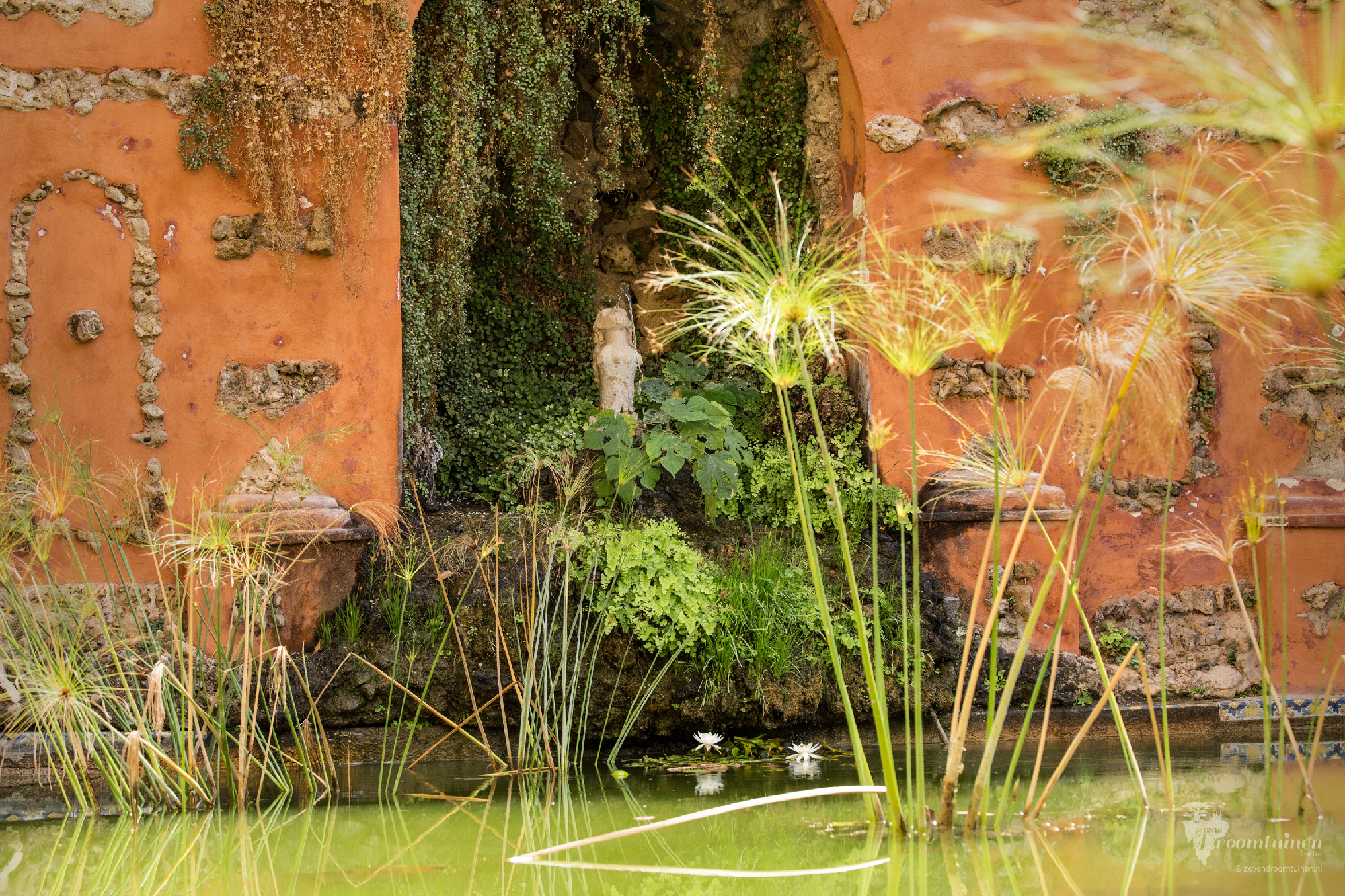 Een waterfontein in de tuin van Real Alcázar, het koninklijke paleis van Sevilla, Spanje. Ik vind het bijzonder om te zien hoe de natuur de scene verrassend maakt en de verwering juist voor schoonheid heeft gezorgd.